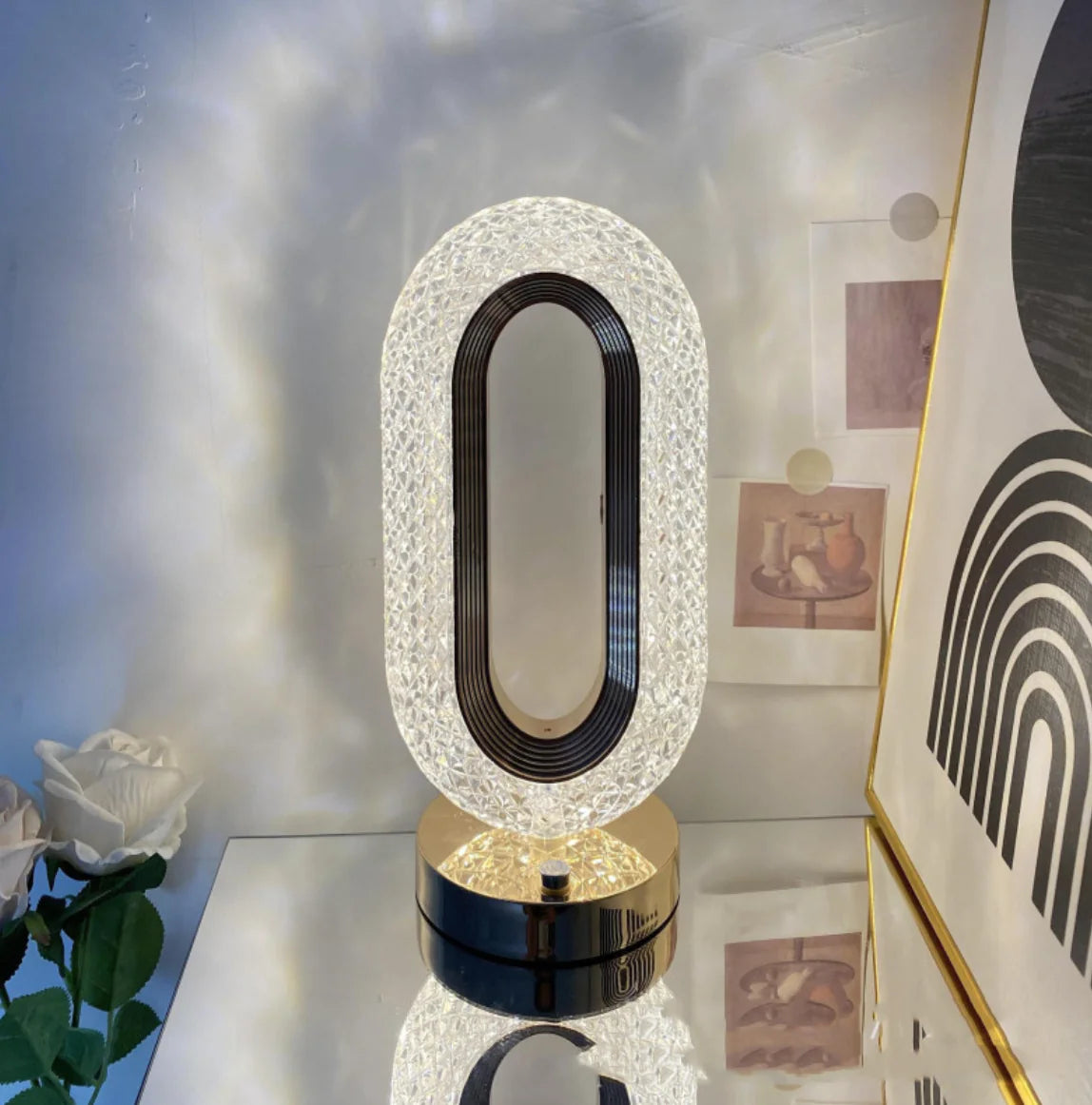 Elegant crystal touch lamp with oval design and black base glowing warmly on a side table