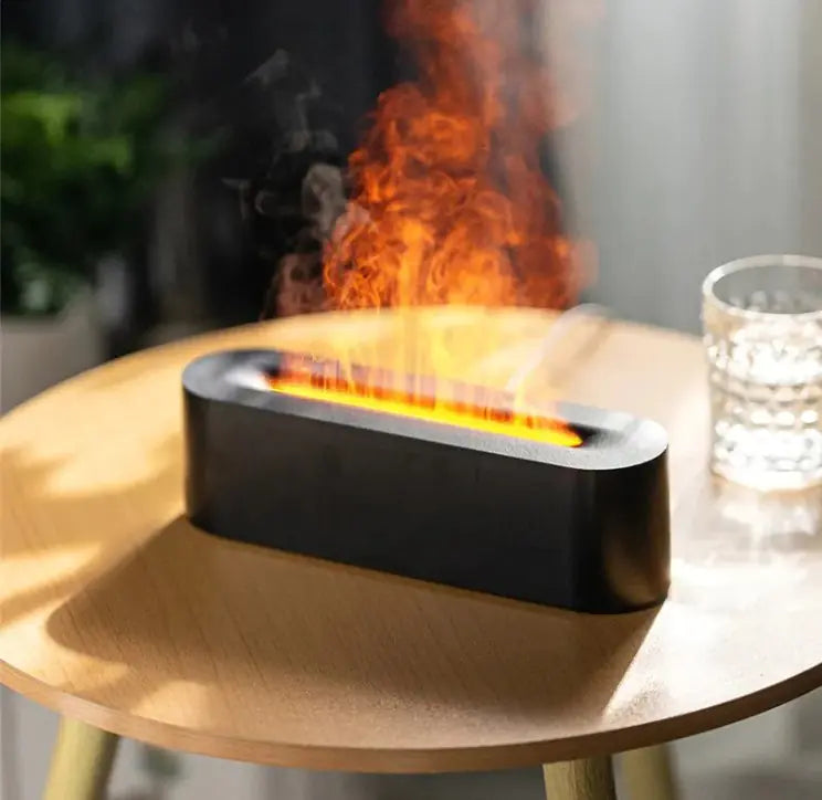Black FlameGlow aroma diffuser emitting warm orange flame mist on a bedside table.